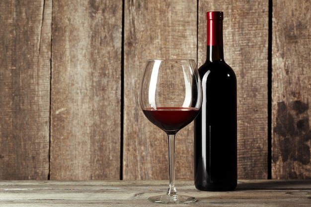 Glass and bottle with delicious red wine on table