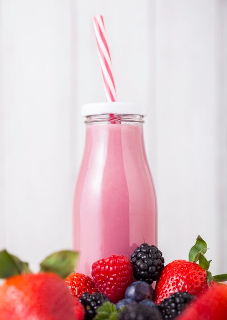 Glass bottle with fresh summer berries smoothie on wooden table.Strwberries and raspberies with blueberries and blackberries.