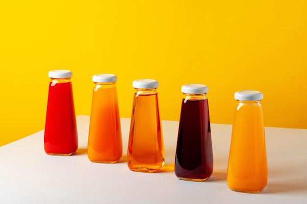 Photo glass bottle with juice on white table against yellow background