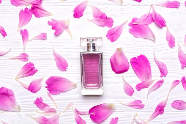 Photo glass bottle with perfume and petals of a peony flower on a white background