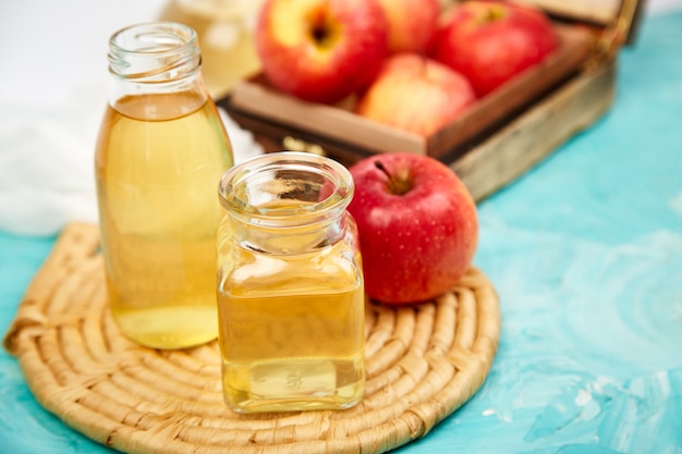 glass bottles of apple organic vinegar and red apples