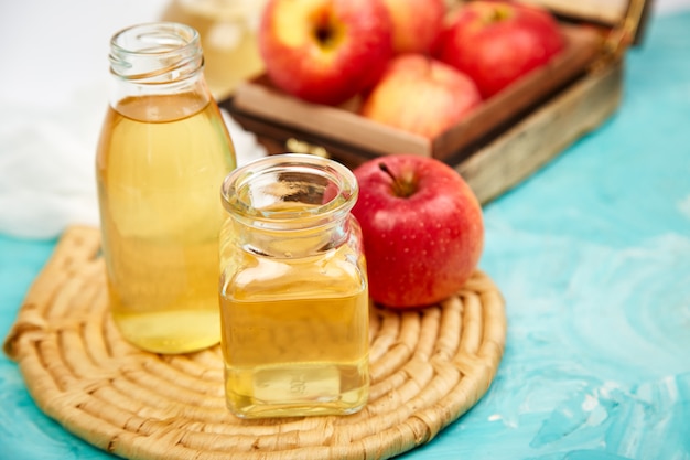 Glass bottles of apple organic vinegar and red apples