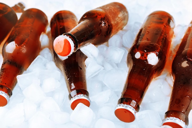 Glass bottles of beer with ice cubes closeup