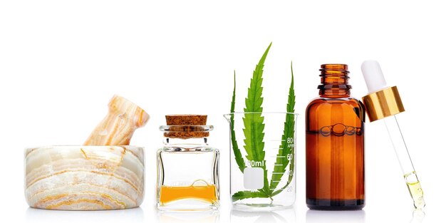 Glass bottles of cannabis oil and hemp leaves isolated on white background Concept of using hemp in medicine