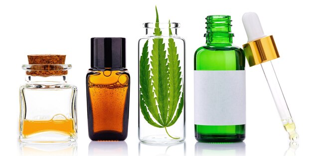 Glass bottles of cannabis oil and hemp leaves isolated on white background Concept of using hemp in medicine