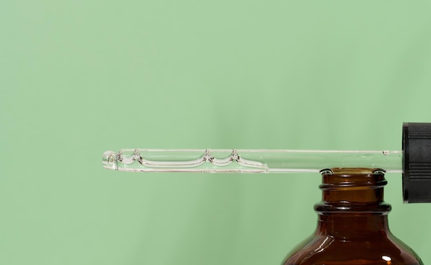 Glass bottles for cosmetics oils with a pipette on a green background