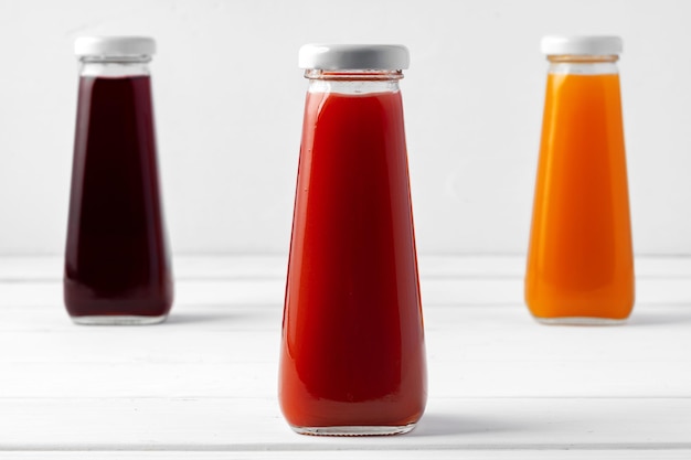 Glass bottles of different juices on white background