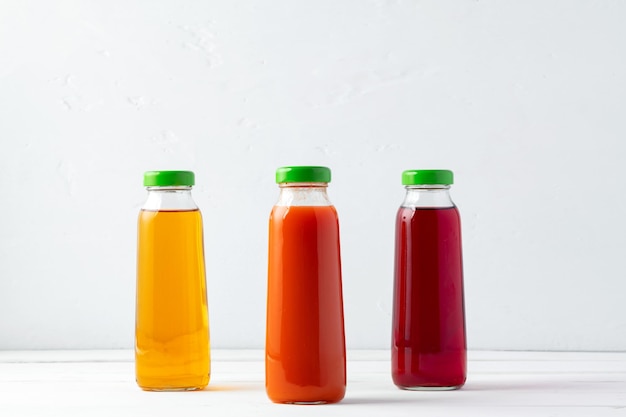 Glass bottles of different juices on white background