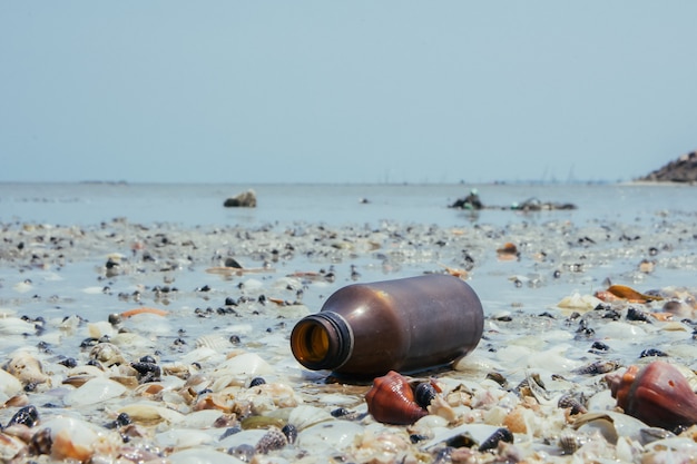 바다에 버려진 유리 병, 쓰레기가 해변에 있습니다.