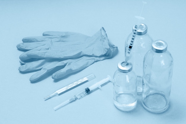 Glass bottles for liquid medicine, syringes for injection, a thermometer and latex gloves