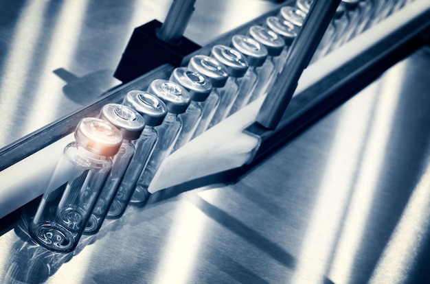 Photo glass bottles in production in the tray of an automatic liquid dispenser, a line for filling medicines against bacteria and viruses, antibiotics and vaccines.