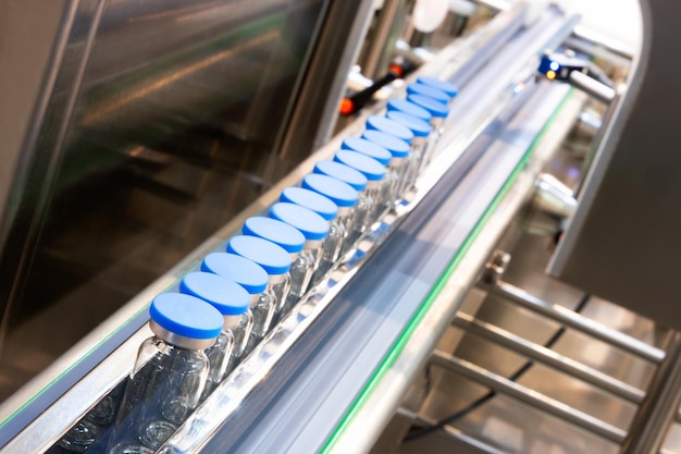 Photo glass bottles in production in the tray of an automatic liquid dispenser, a line for filling medicines against bacteria and viruses, antibiotics and vaccines.