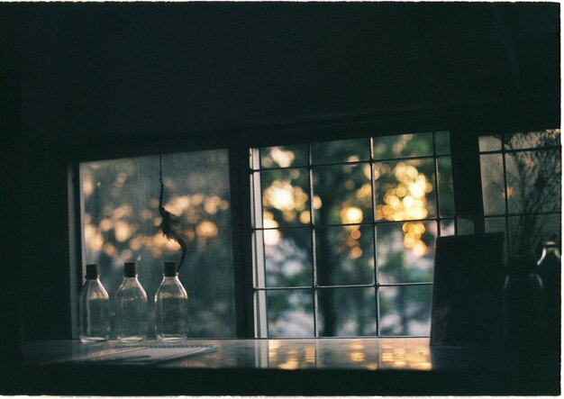 Photo glass bottles on table by glass window