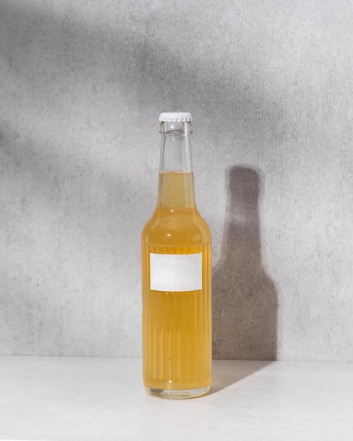 Glass bottles with blank label and liquid similar to lemonade beer or kombucha on grey background