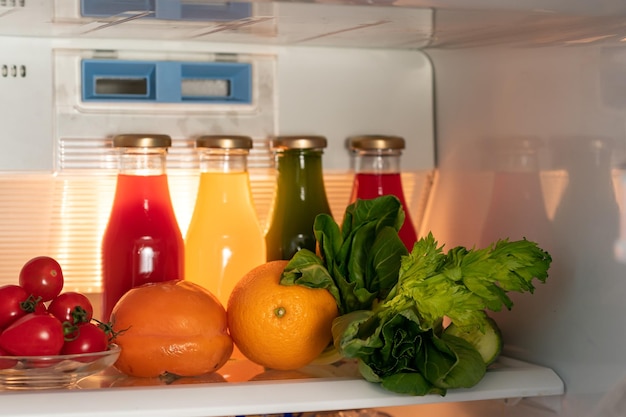 glass bottles with colorful fresh juice fruit and vegetable smoothies in the refrigerator