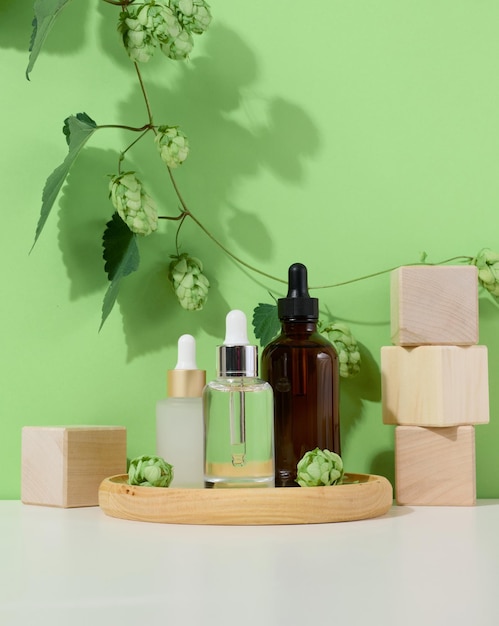 Glass bottles with pipettes for liquid cosmetics on a wooden stand