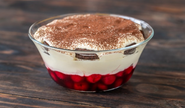 Foto ciotola di vetro di dessert con biscotti, ciliegie e crema di formaggio