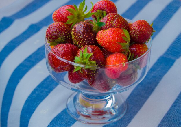 Glass bowl of fresh ripe strawberries on the tablecloth