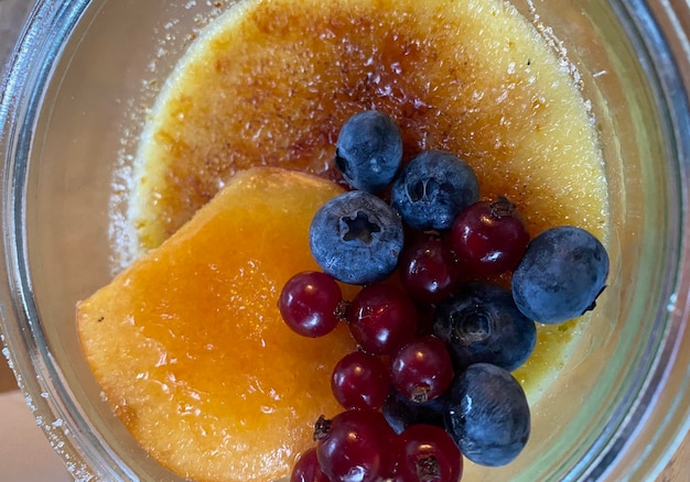 A glass bowl of fruit with blueberries and pineapples.