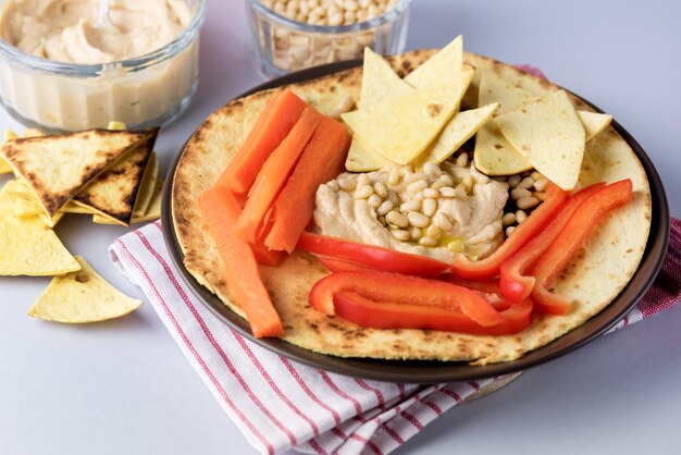 Glass Bowl of Hummus Chickpea Dip Nuts Paprika Carrots and Olive Oil With Pita or Chips