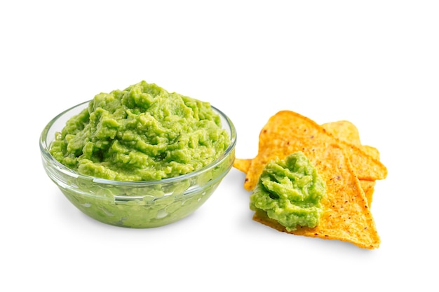 Glass bowl of mexican guacamole dipping sauce served with nacho chips isolated on white background