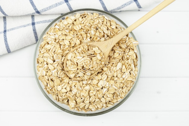 Glass bowl of oatmeal and a wooden spoon. View from above. Healthy food concept, breakfast with cereals. Food for allergy sufferers and vegetarians.