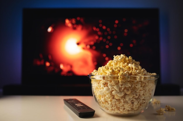 A glass bowl of popcorn and remote control in the background
the tv works evening cozy watching a movie or tv series at
home