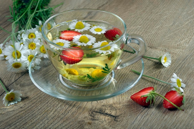 A glass bowl of tea with a bunch of daisies in it