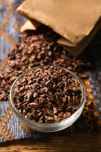 Glass bowl with cocoa nibs on table