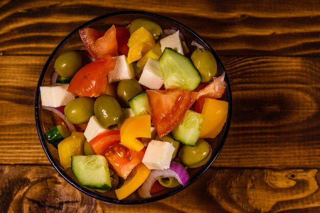 Glass bowl with greek salad on wooden table top view