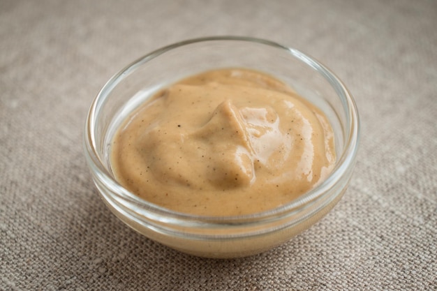 A glass bowl with mustard on canvas background