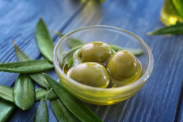 Foto ciotola di vetro con olive e olio su sfondo di legno