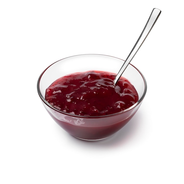 Glass bowl with red fruit jam close up on white background