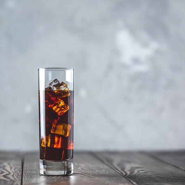 Glass of brew cold coffee and ice Cold summer drink on a dark wooden table and gray background with copy space