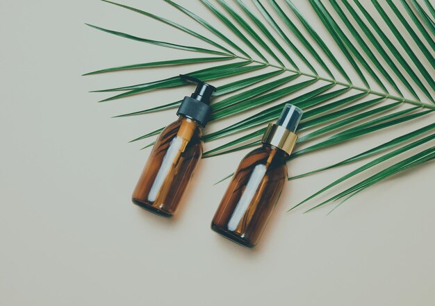 Glass brown cosmetic bottles with spray and dispenser on a gray background, top view. Containers for liquid products