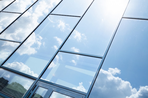 Foto facciata della costruzione di vetro con la riflessione del cielo blu