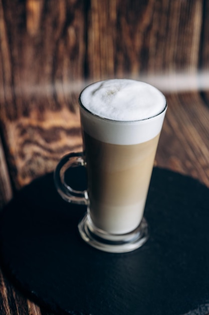 A glass of cappuccino with a foamy cappuccino on top.