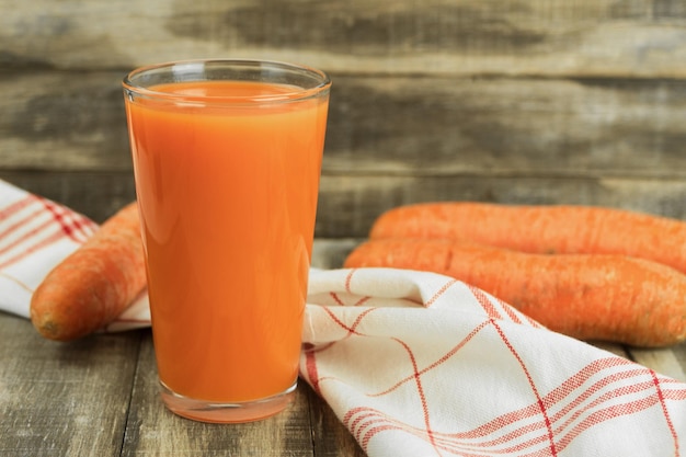 A glass of carrot juice on a rustic background