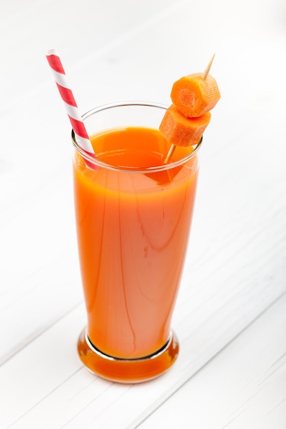 Glass of carrot juice on the white table