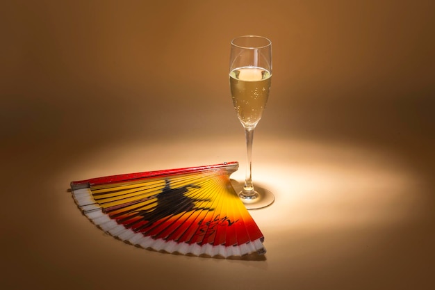 Glass of cava next to a fan that bears the colors of spain and a drawn bull