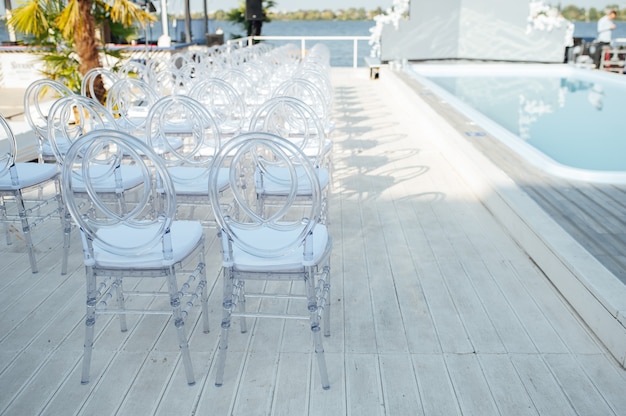 Glass chairs stand in a row in a beautiful wedding outing ceremony.