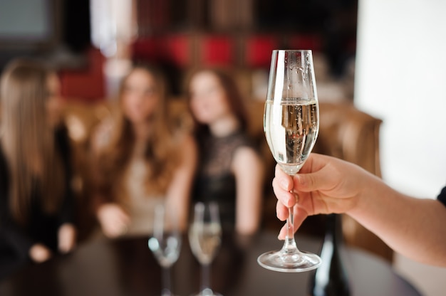 Bicchiere di champagne sullo sfondo di amici a una festa