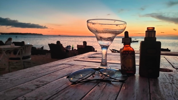 샴페인 한 잔과 술 한 병이 해변의 탁자 위에 놓여 있습니다.