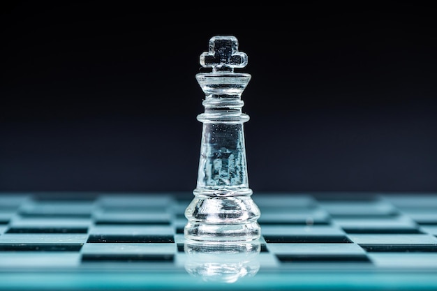 glass chess board game in black background selective focus on king leadership concept