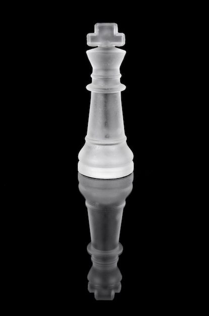 Glass chess king on black isolated background.