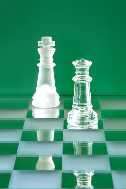 Glass chess king and queen pieces in shades of green. Male-female equality concept.