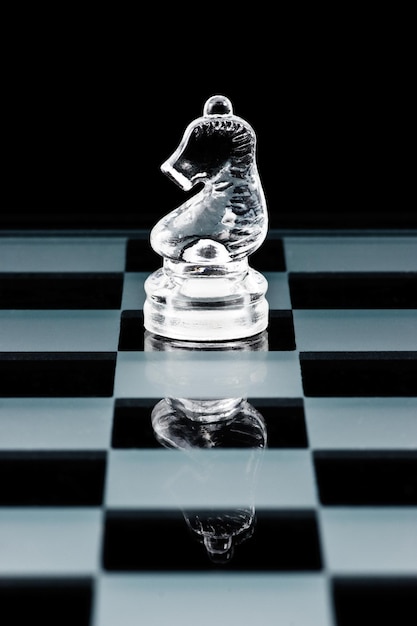 Photo glass chess piece knight on glass board