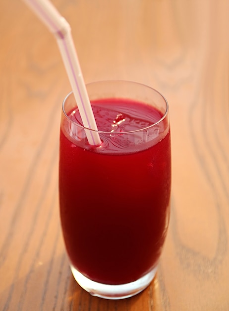 Стакан охлажденного яркого красного гранатового сока на деревянном столе