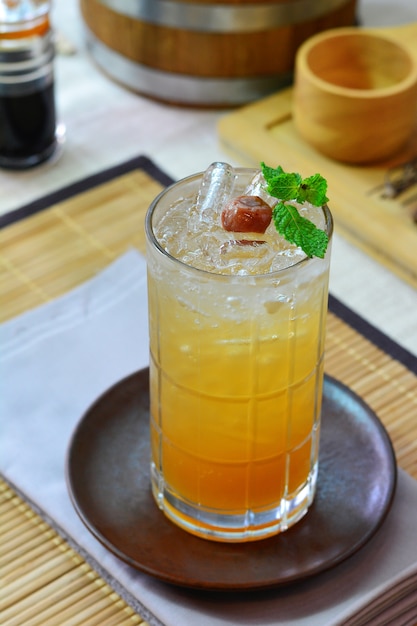 Glass of Chinese plum on round glass coaster, Napery and bamboo plate mat