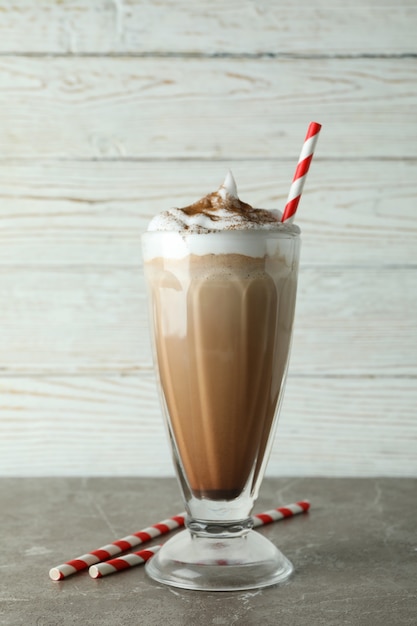 Glass of chocolate milkshake and straws on gray table